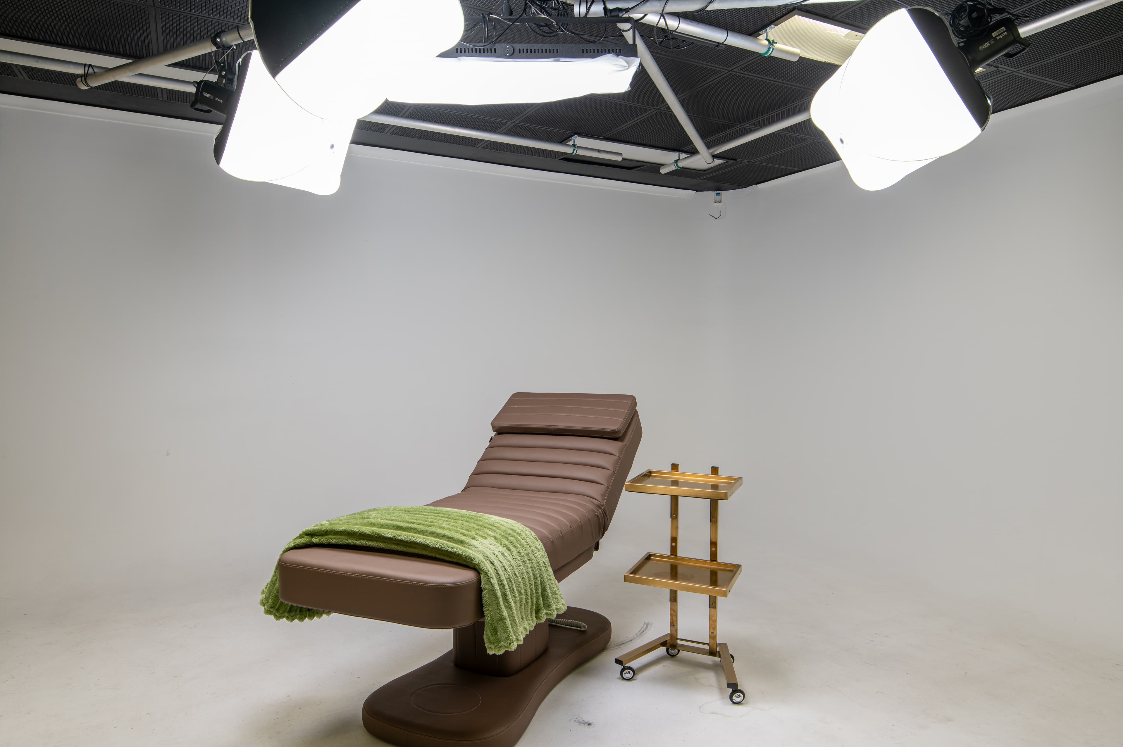 Creative studio with professional softbox lighting around a treatment bed on white cyc